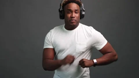 Dancing of a black man on a gray background with headphones Stock Footage 220354673