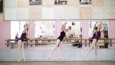 In dancing hall, Young ballerinas in purple leotards perform grand battement Stock Footage 89014677