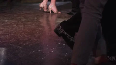 Dancing legs of unknown couple enjoying the tango in dark hall. Video stock 169494820