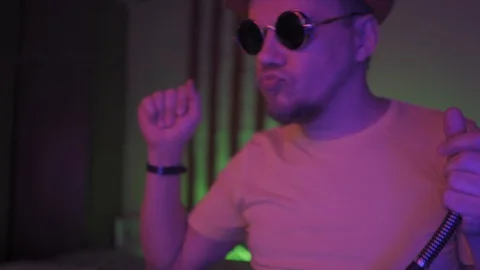 Dancing smoking hookah man wearing sunglasses in dark room wearing hat working Stock Footage 130126532