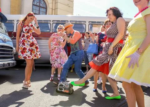 Dancing stilyogs in retro suits at the buses. 库存照片