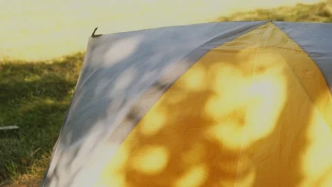 A dancing sunny beams looking through tree shadows on the colored tent at noon Stock Footage 151100258