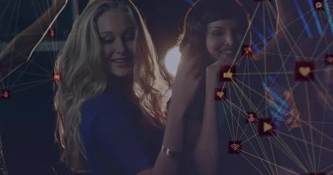 Dancing two friends in evening attire in nightclub, with glowing digital icons Stock Photos