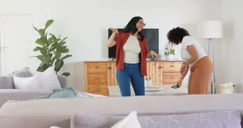 Dancing two women clapping, placing smartphone on coffee table, adjusting Stock Footage 337026285