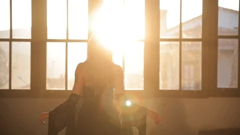 Dancing woman dancing in front of large windows as the sun goes down 库存影片 128661341