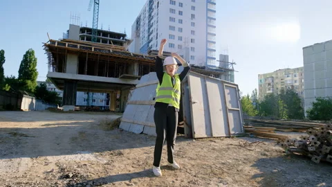 Dancing young engineer lady with a safety helmet and goggles on the construction Stock Footage 152077989
