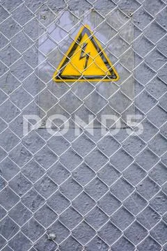 Danger of electrocution yellow sign on gray. High voltage warning sign Stock Photos