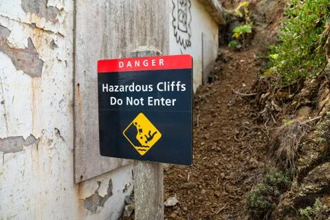 Danger hazardous cliffs do not enter with person falling sign next to concrete Stock Photos