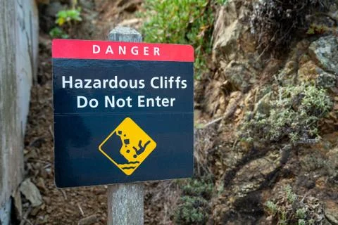 Danger hazardous cliffs do not enter with person falling sign on wooden post Foto stock