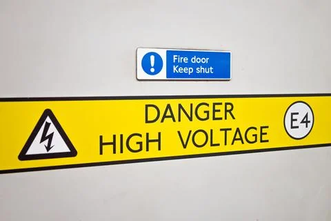 Danger high voltage warning sign on fire door Stock Photos