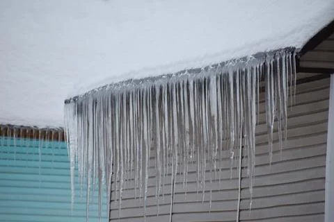 Danger of large icicles falling on people's heads. ice hangs from  roof in wi Stock Photos