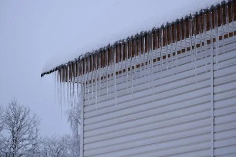 Danger of large icicles falling on people's heads. ice hangs from  roof in wi Stock Photos