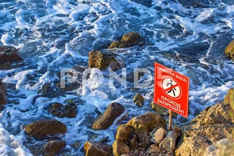 Danger! no walking sign on the rocky sea coast Stock Photos