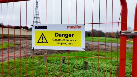 A danger sign is attached to an orange security fence at a construction site in Stock Footage 328148964