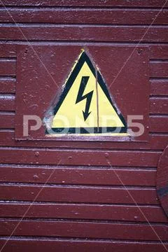 Danger sign high voltage arrow on dirty wooden door Stock Photos
