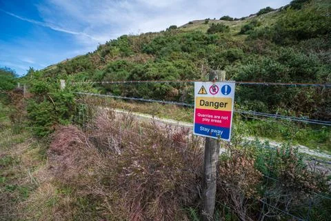 Danger warning sign on barbed wire fence at Blackpool Lake clay pits, Cornwall Stock Photos