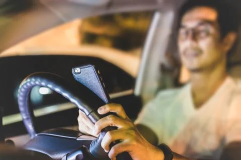 Dangerous concept man using cell phone while driving at night. Stock Photos