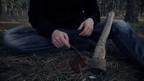 Dangerous criminal sits and enjoys sight of bloody axe after murder in forest Stock Footage