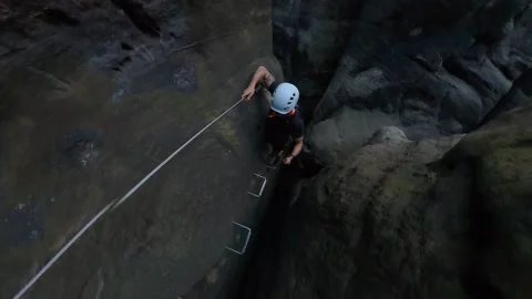 Dangerous via ferrata climb between rocks dark trail - young man Stock Footage 194579382