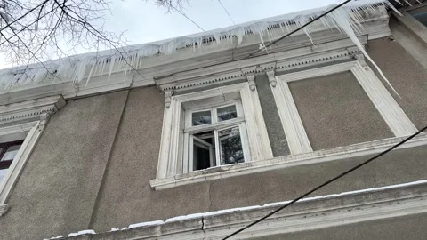Dangerous icicles hanging from old building roof Stock Footage 328477233