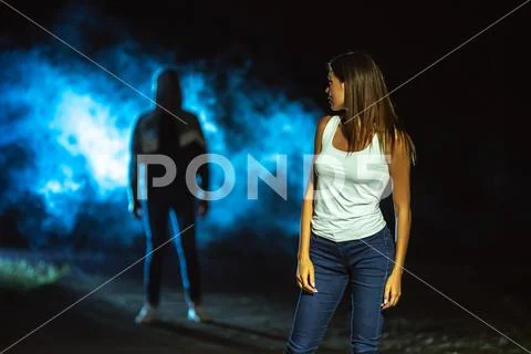 The dangerous man standing behind the woman on the dark street Stock Photos