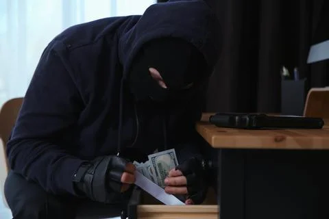 Dangerous masked criminal stealing money from house Stock Photos