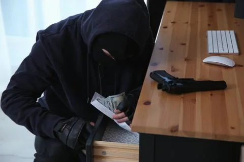 Dangerous masked criminal stealing money from house Stock Photos