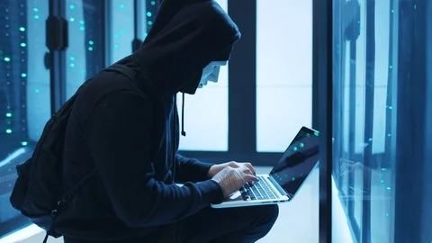 Dangerous masked spy computing and coding on laptop, running ransomware to steal Video stock 120604271