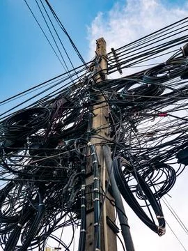 Dangerous overloaded utility pole with excessive tangled electrical wiring .. Foto stock