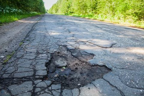 Dangerous pothole in the asphalt rural road. Road damage Stock Photos