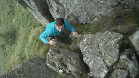 Dangerous rock climbing in the mountains Man climbs a mountain in cloudy weather Stock Footage 218441653