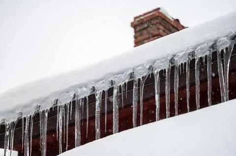 Dangerous sharp icicles and snow hanging from the roof. 写真素材
