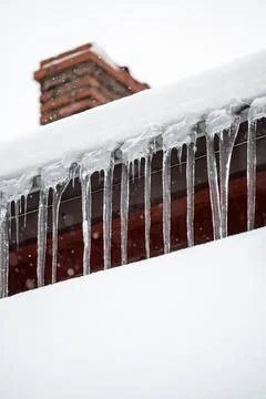 Dangerous sharp icicles and snow hanging from the roof. 写真素材