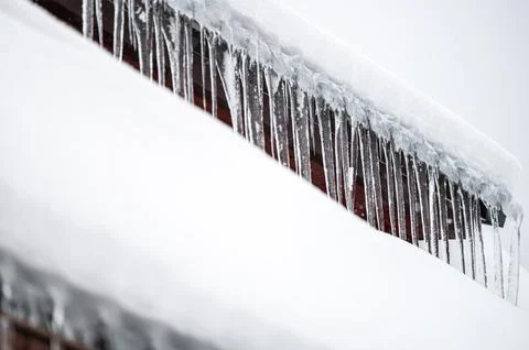 Dangerous sharp icicles and snow hanging from the roof. 写真素材
