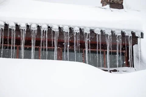 Dangerous sharp icicles and snow hanging from the roof. 写真素材