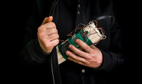 Dangerous terrorist in black jacket with dynamite bomb in hand isolated on black Stock Photos