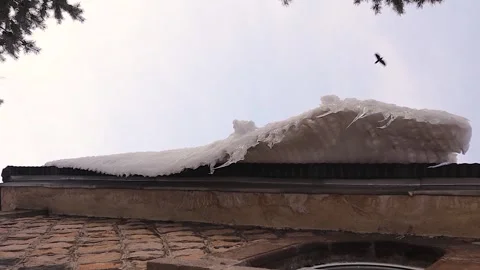 Dangerous Thick Ice Layer and Sharp Icicles Hanging Over Snowy Stone Roof Stock Footage 328579599