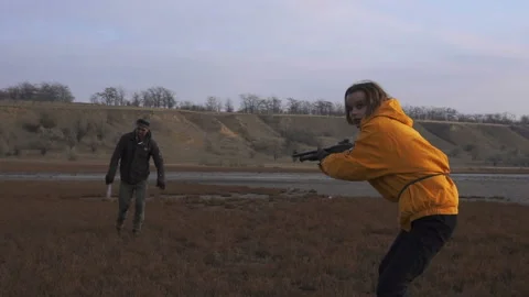 Dangerous zombie monster with Machete attacking blonde girl with shotgun. Horror Stock Footage 103386510