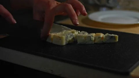 Danish blue cheese being cut into cubes on a cutting board. 4K video. Artistic Stock Footage 146488230