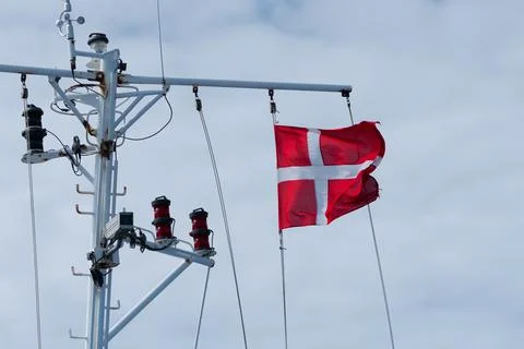 Danish flag waving in the wind with cloudy sky in the background. Stock Photos