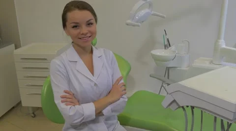 Dantist in Lab Coat is Sitting Her Arms Crossed and Smiling Girl on a Green Stock Footage 60990624