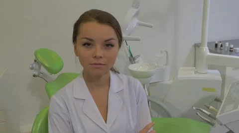 Dantist in Lab Coat is Smiling Sitting on a Chair at Dental Treatment Room Stock Footage 60980288