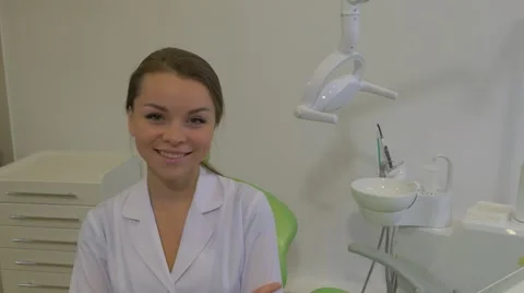 Dantist in Lab Coat is Smiling Sitting on a Green Chair at Dental Treatment Stock Footage 60981692