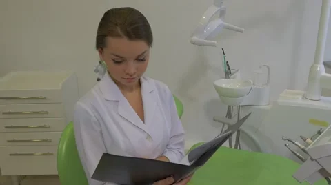 Dantist is Reading a Notes in a Fold Raises Head Girl in Lab Coat is Smiling Stock Footage 60980983