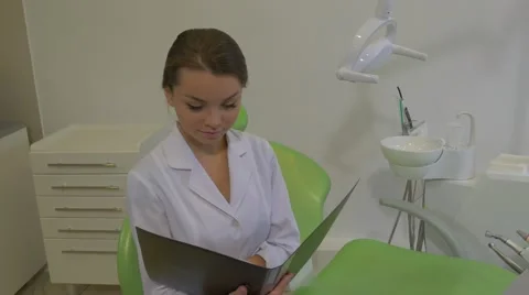 Dantist is Reading a Notes in a Fold Smiling Raises Head Girl in Lab Coat is 動画素材 60980180