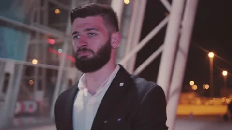 A dapper and stylish man dressed elegantly at night amidst a vibrant modern Stock Footage 345494066