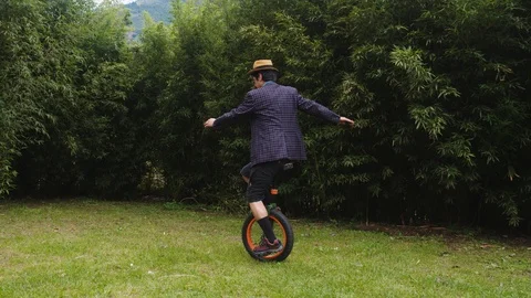 A dapper man practicing his new learned skill on a monocycle in ecuador Видео 113937528