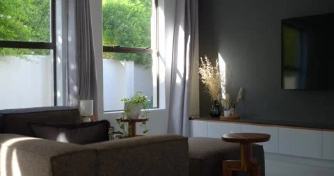 Dappled sunlight is shifting across grey sofa and ottoman near window as breeze Vídeos de archivo 341320418