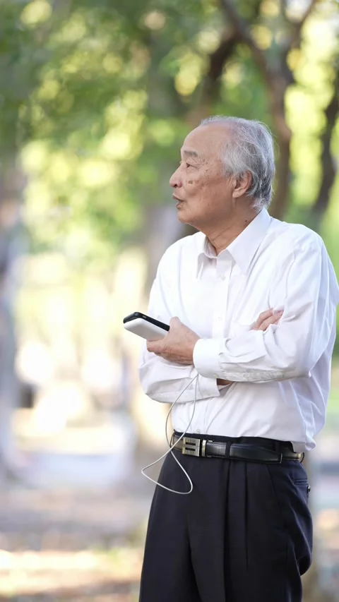In the dappled sunlight of a spring natural park, a Japanese man in his 70s Stock Footage 307830957