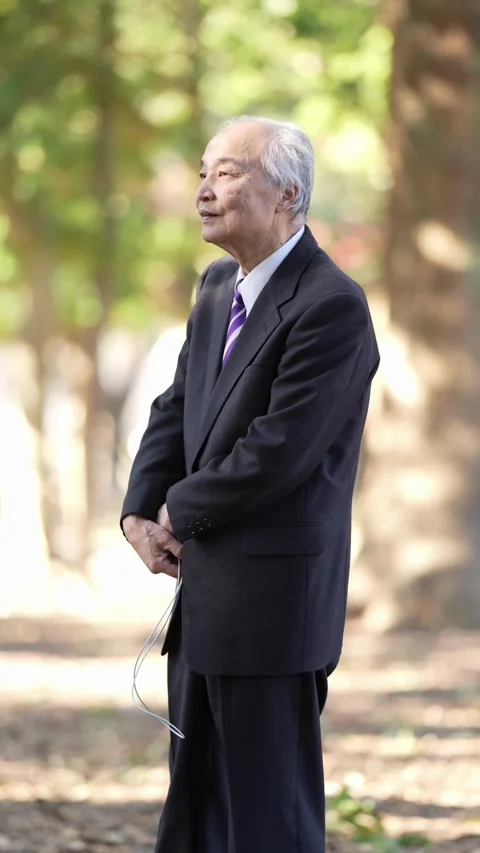 In the dappled sunlight of a spring natural park, a Japanese man in his 70s Vídeos de archivo 307888639
